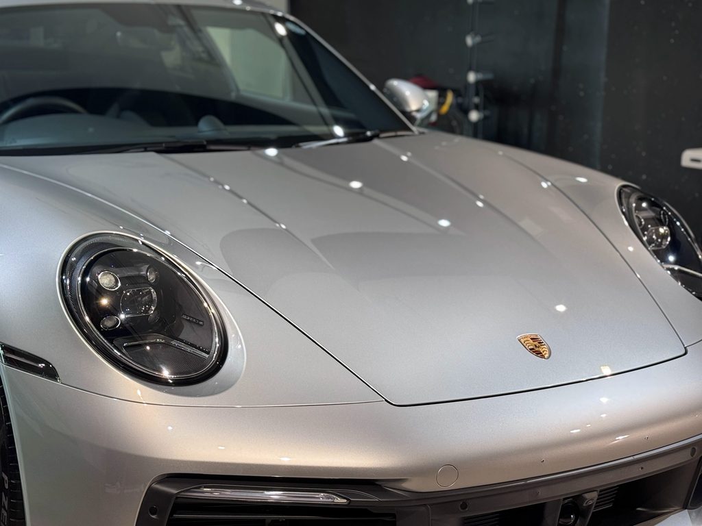 ポルシェ911(992型)シルバー 研磨とTEVOナノクォーツコーティング施工後のボンネット 照明が映り込む艶